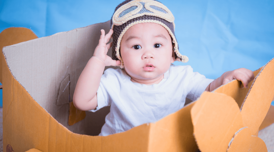 Baby sitting inside a homemade cardboard box airplane